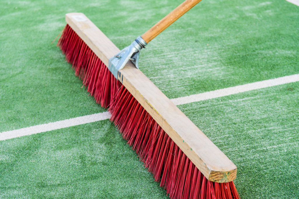 Brushing artificial turf fibers upright as part of routine maintenance