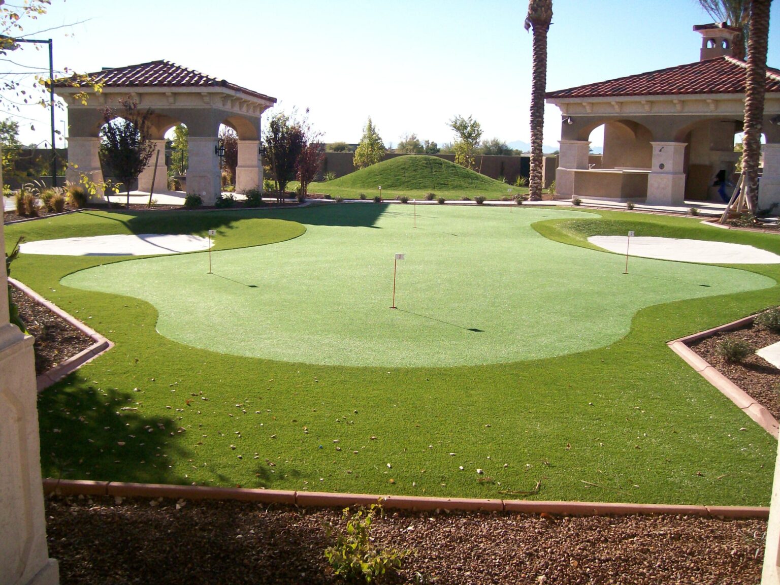 Putting greens installed by Turfscapes of Arizona featuring multiple sand traps and rolling hills in high end Phoenix backyard home.